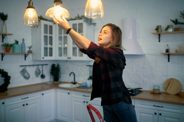 Woman adjusting a lightbulb in her kitchen