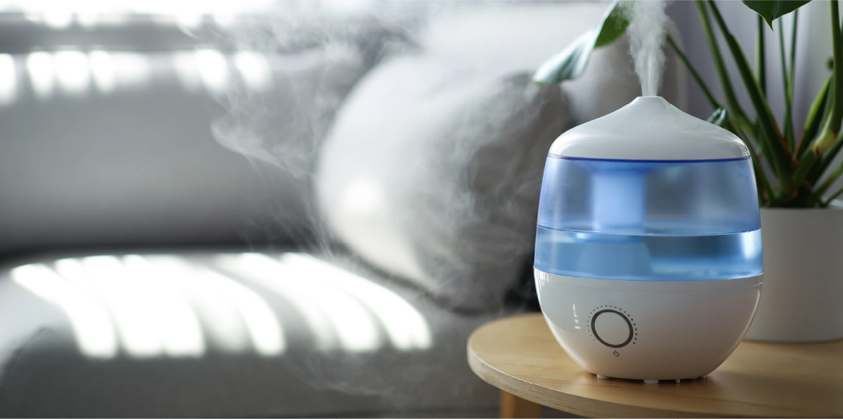 A white and blue humidifier sits on top of a wooden coffee table in a living room.