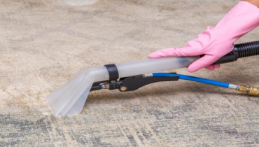 Pink-gloved hand cleaning carpet